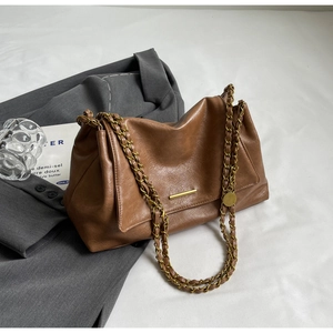 Macro shot of caramel leather crossbody bag with lychee texture and gold chain detail
