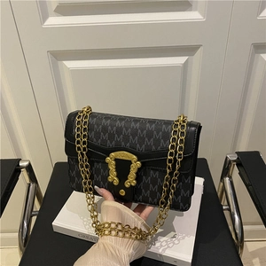 Vintage black chain shoulder bag with M pattern and golden buckle on white book
