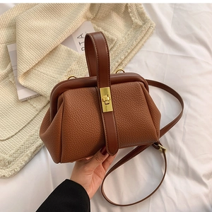 Close-up of brown litchi grain leather doctor bag with metal lock and adjustable strap