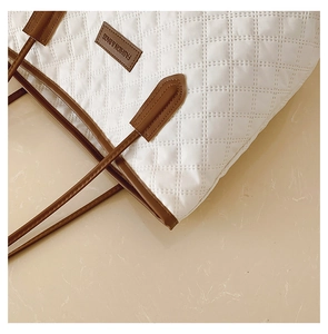 Detail of white quilted tote bag with brown leather patch and premium diamond stitching