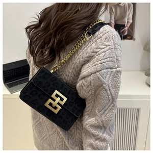 Detail of black leopard velvet bag with gold geometric metal clasp and chain strap