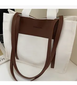 Detail of canvas tote bag with brown leather trim and dual handles on a desk