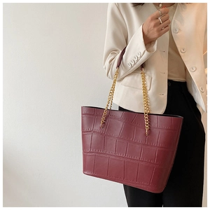Close-up of burgundy tote bag with crocodile pattern texture and gold chain strap