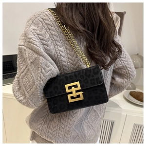 Detail of black leopard print suede crossbody bag with gold chain strap on model