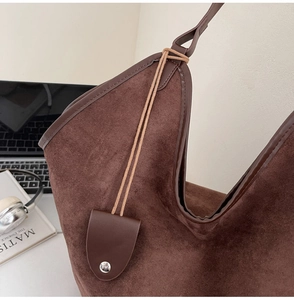 Détail du sac cabas marron foncé en daim avec finitions en cuir et boucles métalliques