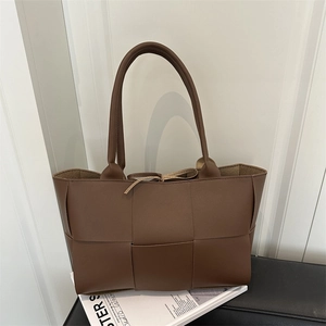 Große dunkelbraune gewebte Leder-Shopper-Tasche mit langen Henkeln auf Bank