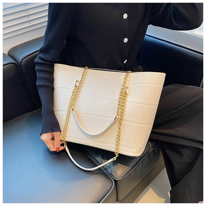 Close-up of white crocodile embossed tote bag with decorative chunky gold chain handle