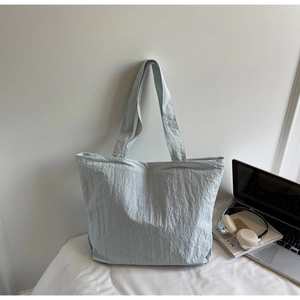 Detailed view of light blue tote bag with wrinkled texture, laptop and accessories