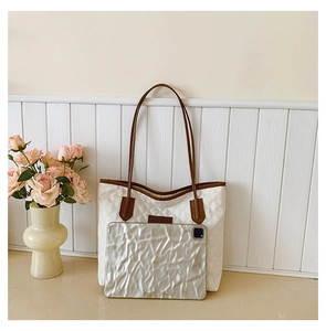 Close-up of quilted tote bag featuring brown leather straps and spacious white interior