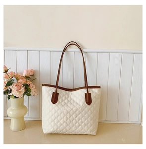 Close-up of quilted cream tote bag featuring textured leather and brown straps