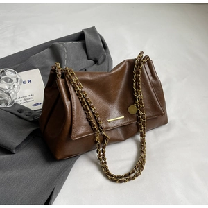 Detail of vintage brown PU leather bag with gold chain straps and textured finish