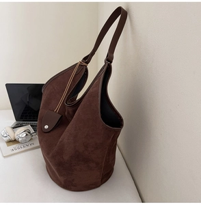 Détail d'un sac cabas en cuir mat marron avec bordures contrastées et petite pochette assortie