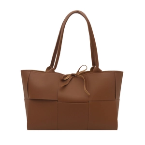 Minimalist brown woven leather tote bag with wide straps and decorative bow tie detail