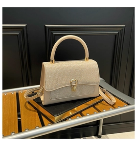 Detailed view of luxury creamy white handbag featuring sparkling silver rhinestones and gold clasp