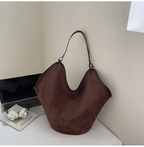 Détail d'un grand sac cabas en daim marron foncé dans un cadre de vie professionnelle