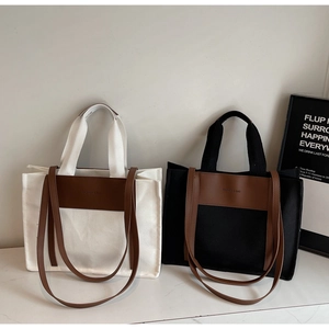 Detail of minimalist canvas tote bags in black and cream with faux leather trim and straps