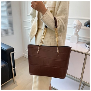 Close-up of deep brown crocodile pattern tote bag with luxury gold chain strap