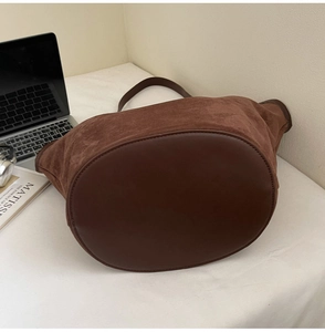 Détail d'un sac seau vintage en daim marron avec finitions cuir et longue bandoulière