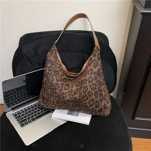 Chic leopard print velvet tote bag with brown leather straps shown on a stylish chair