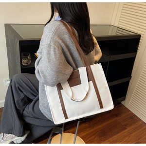 Detail of canvas tote bag with brown leather trim and fashion lettering on back of model