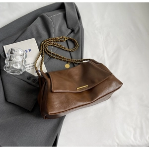 Detail of vintage brown tote bag texture with golden chain strap on a stylish blazer
