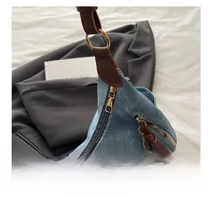 Detail of smooth metal zipper and blue denim fabric on retro crossbody tote bag