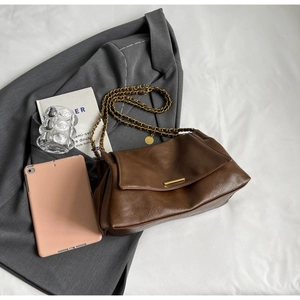 Detailed top view of brown leather shoulder bag with gold chain strap and props.