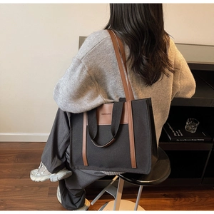 Detail of black canvas tote bag with leather handles and Fashion & Bag lettering