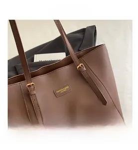 Détail d'un sac cabas marron avec texture cuir et bandoulière à boucle dorée