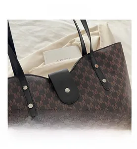 Detail of the brown M-pattern tote bag with silver rivets and magnetic snap closure