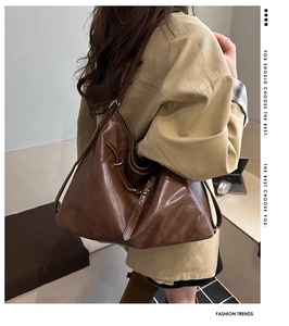 Detail of vintage brown leather tote showing metal chain buckle and sleek shoulder strap
