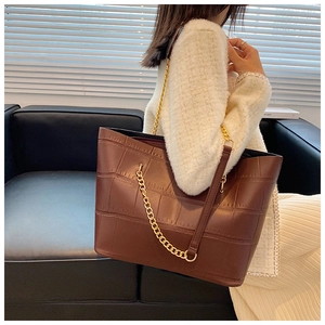Detail of brown crocodile pattern tote bag featuring gold chain and leather shoulder strap