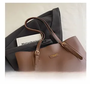 Détail du cabas en cuir mat marron avec bandoulière réglable et logo doré imprimé