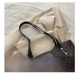 Detail of vintage brown tote bag with M-pattern print and black leather handles