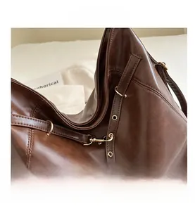 Close-up of fine stitching and gold metal hardware on the dark brown leather tote bag