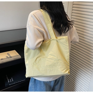 Detail of light yellow tote bag with heart embroidery and soft nylon texture