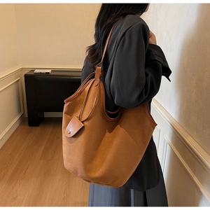 Détail d'un grand sac cabas en daim marron avec fines bandoulières et petite pochette assortie
