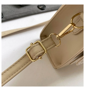 Detail of premium golden hardware and precise stitching on beige crossbody bag strap