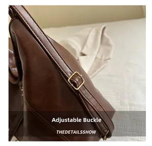 Detail of adjustable gold buckle and dark brown leather shoulder strap on a tote bag