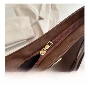 Close-up of smooth gold zipper and dark brown leather texture on a tote bag