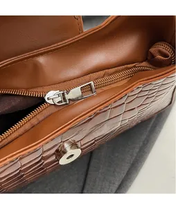 Close-up of silver metal zipper and magnetic buckle on brown crocodile pattern bag