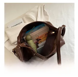 Detail view of large capacity dark brown leather tote bag with books and daily essentials