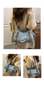 Detail of blue denim tote bag featuring pearl chain and brown leather shoulder strap