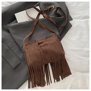 Detail of dark brown suede shoulder bag with long fringes on a stylish grey blazer