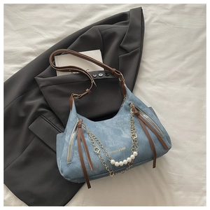 Detail of light blue denim tote with brown leather strap and decorative pearl chains
