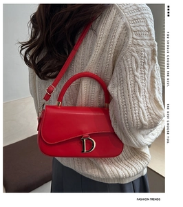 Gros plan d'un sac à main en cuir rouge avec une boucle métallique dorée en forme de D