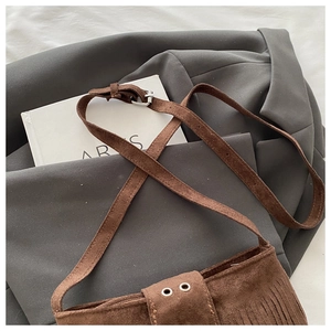 Close-up of brown suede shoulder bag featuring long fringe and silver buckle detail