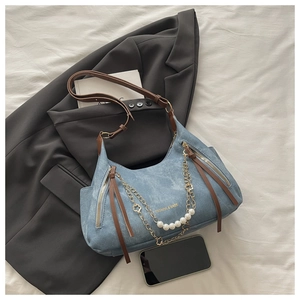 Detail of light blue denim tote bag with pearl chain, floral charms and brown leather straps