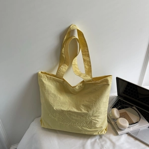 Sac fourre-tout jaune décontracté avec broderie présenté avec un ordinateur