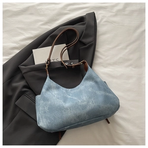 Detail of light blue denim hobo bag with vintage wash and dark brown leather strap